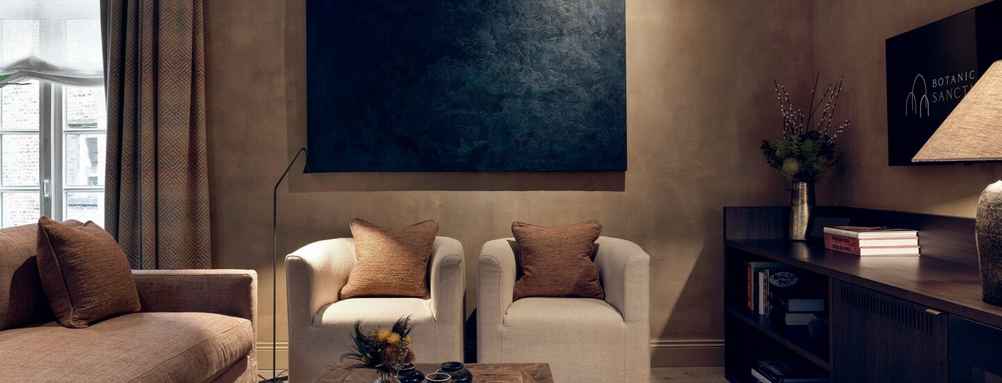 Luxuriöse Hotelsuite mit Designermöbeln in Natur- und Brauntönen und einem Fernseher.