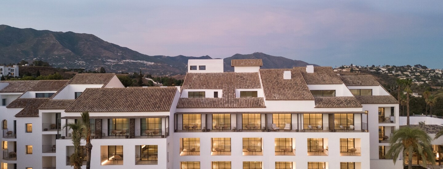 Weißes Hotel am Abend vor einer Bergkulisse