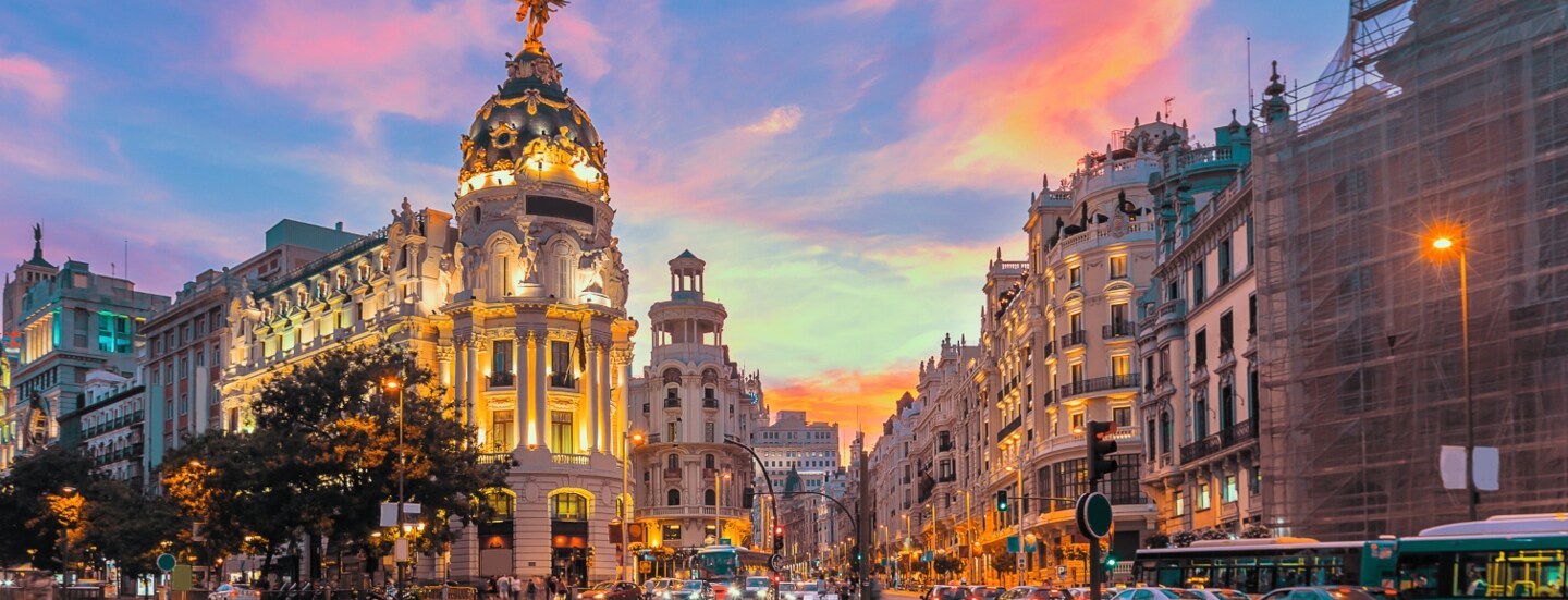 Belebte Kreuzung in einer großen, beleuchteten Stadt, der Himmel strahlt blau und rot