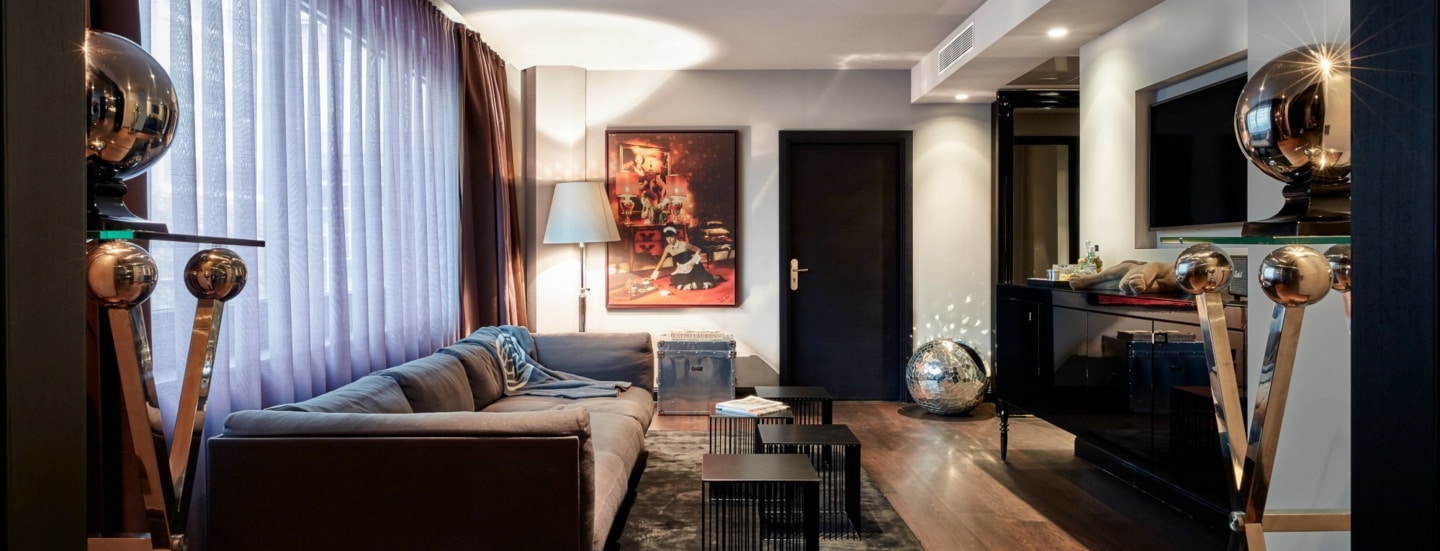 Moderne Hotelsuite mit Kunstwerken und silbernen Dekokugeln.