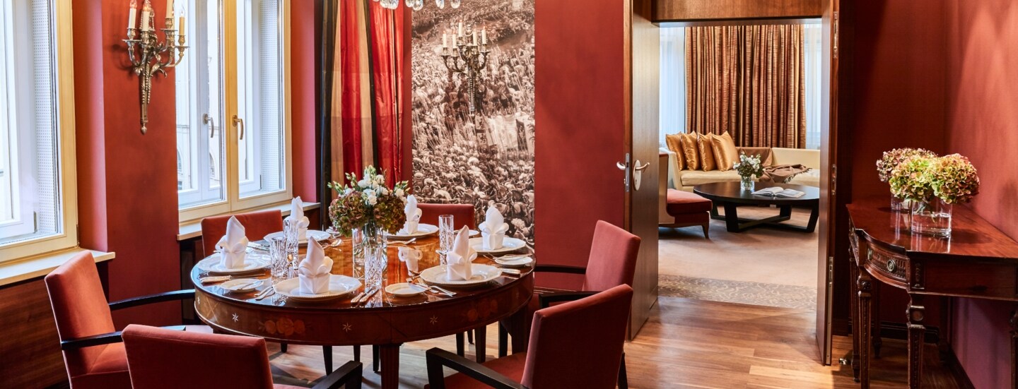 Runder, elegant eingedeckter Esstisch unter einem Kronleuchter in einer luxuriösen Suite in Terrakottatönen.