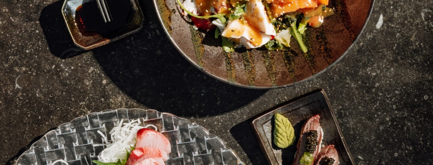 Aufsicht mehrerer Teller mit Sushi und anderer asiatischen Speisen.