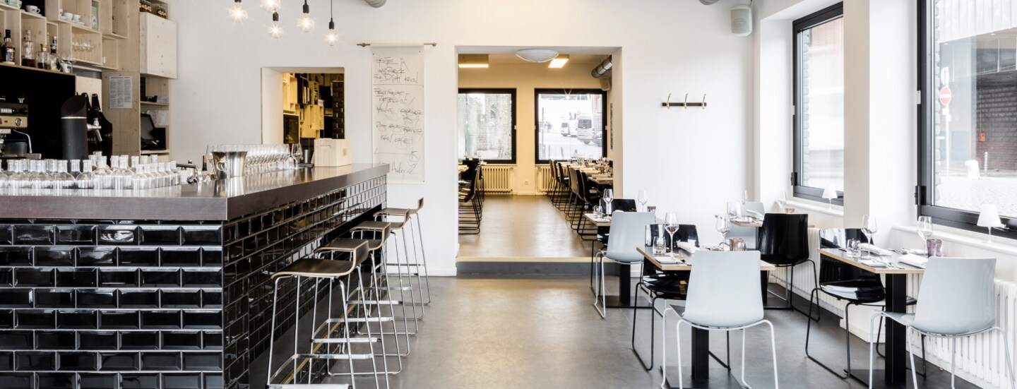 Speiseraum mit Tresen eines modernen Restaurants im industriellen Design und schwarz-weißer Farbgestaltung.