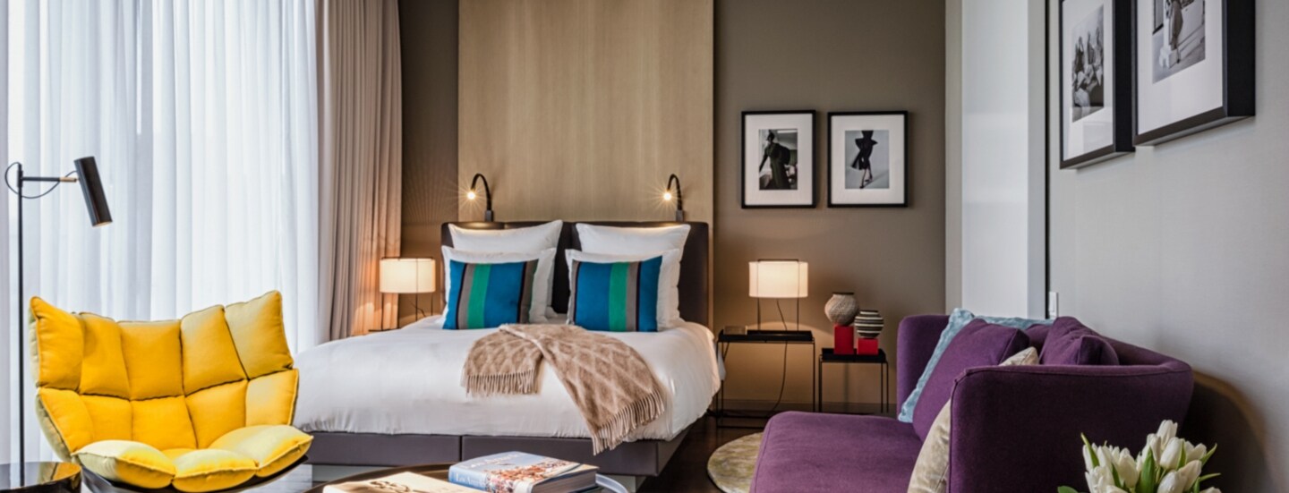 Moderne, helle Hotelsuite mit farbenfrohen Polstermöbeln und Schwarzweißfotografien an den Wänden.