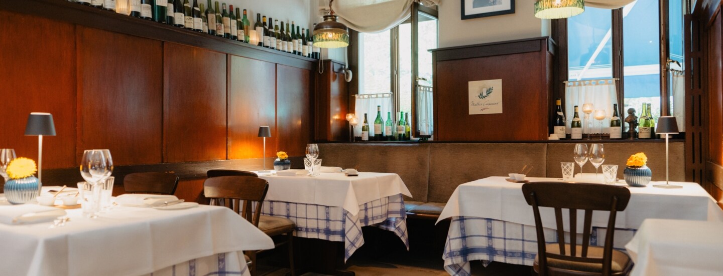 Gemütlicher Speiseraum mit Holzverkleidung und eingedeckten Tischen in einer Brasserie.