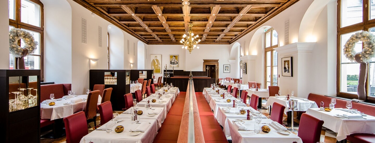 Weiß eingedeckte Tische in dem Speisesaal einer Brasserie mit Kassettendecke.