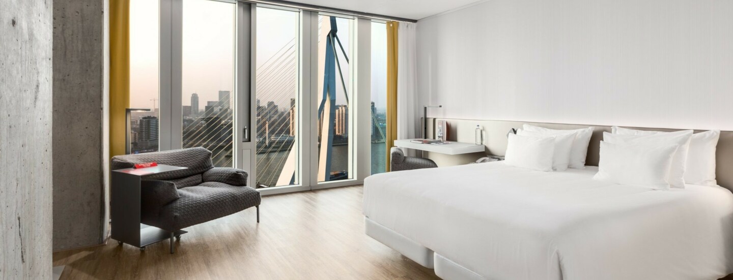 Geräumiges Hotelzimmer des nhow Rotterdam mit Blick auf die Erasmusbrücke.