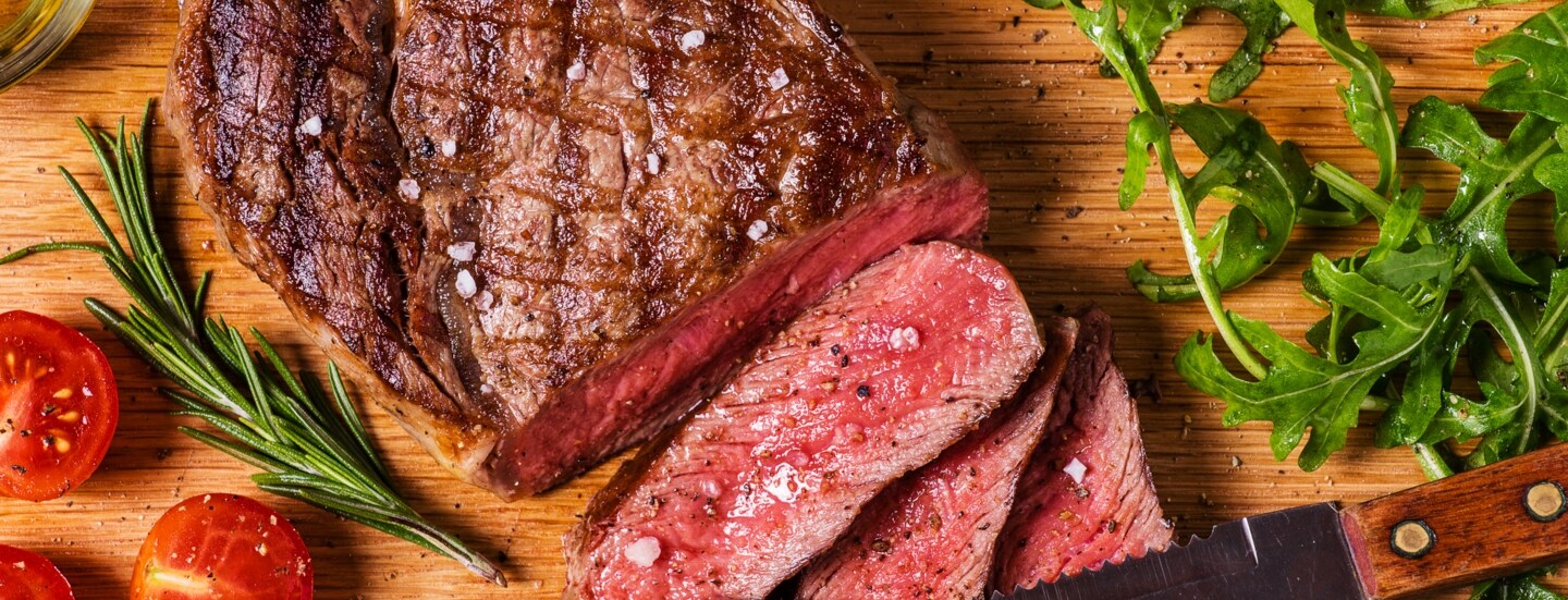 Aufsicht eines gebratenen, angeschnittenen Steaks auf einem Holzbrett.