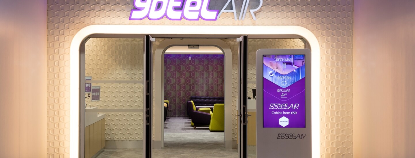 Beleuchteter Eingang zu einer modernen Flughafenlounge von YotelAir.