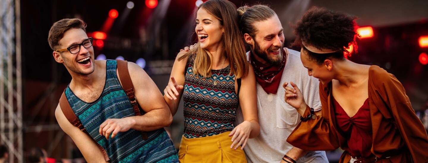 Vier gut gelaunte, junge Menschen auf einem Festival.