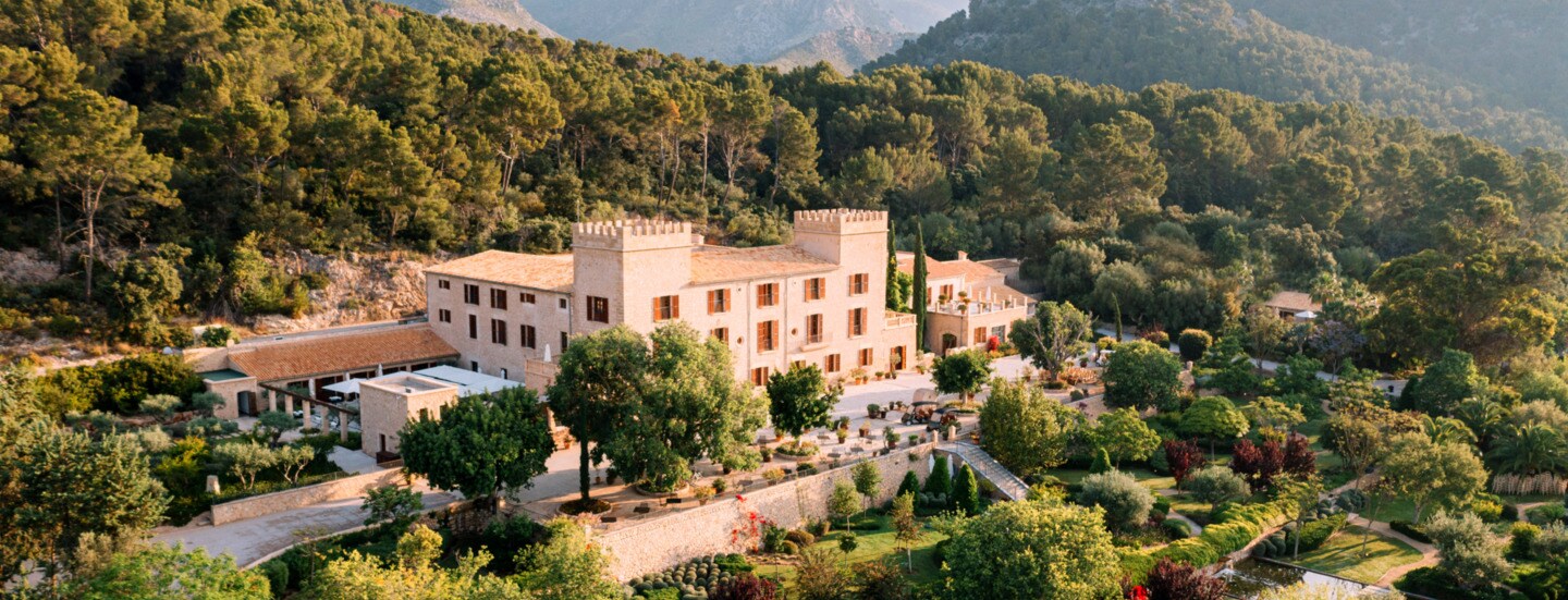 Das historische Hotel Castell Son Claret mit seiner grünen Parkanlage vor der Kulisse des Tramuntana-Gebirges.