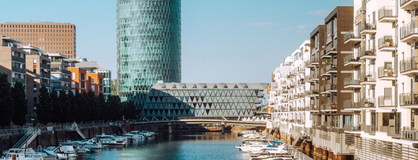 Binnenhafen mit Booten vor Wohnhäusern und einem modernen Gebäudekomplex.