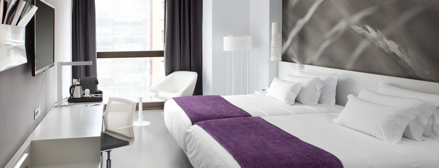 Helles, modernes Hotelzimmer mit Doppelbett.