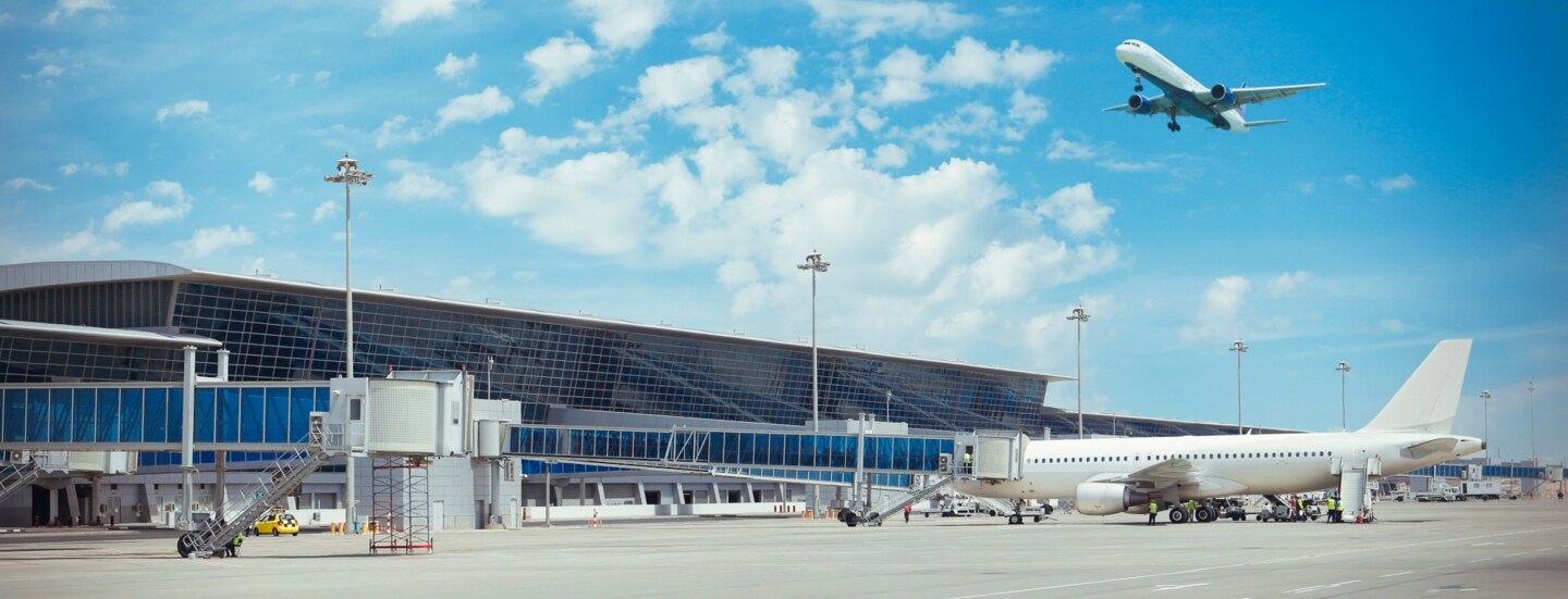 Flughafenterminal, über den ein Flugzeug fliegt.