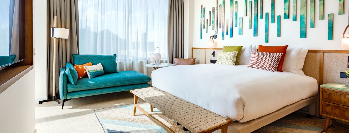 Ein helles, modernes Hotelzimmer mit Doppelbett und farbenfrohen Gestaltungselementen.