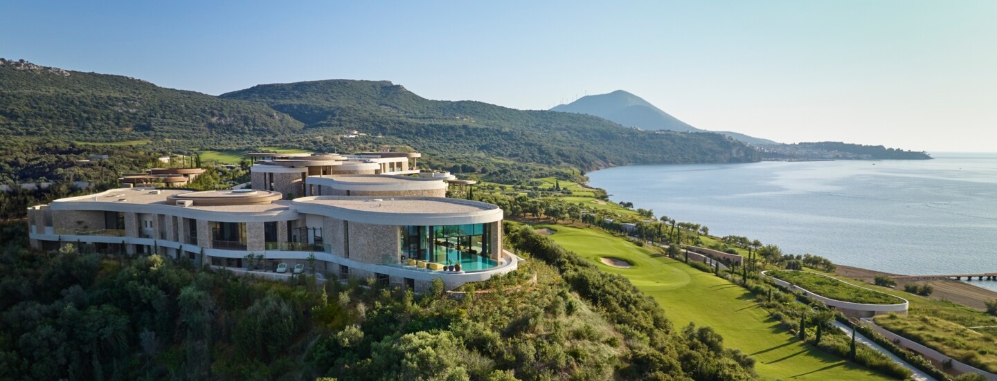 Hotelanlage inmitten einer grünen Hügellandschaft am Meer.