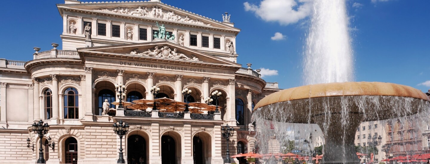 Prachtvolles Operngebäude im Stil der Neorenaissance mit Restaurant, im Vordergrund ein Springbrunnen.