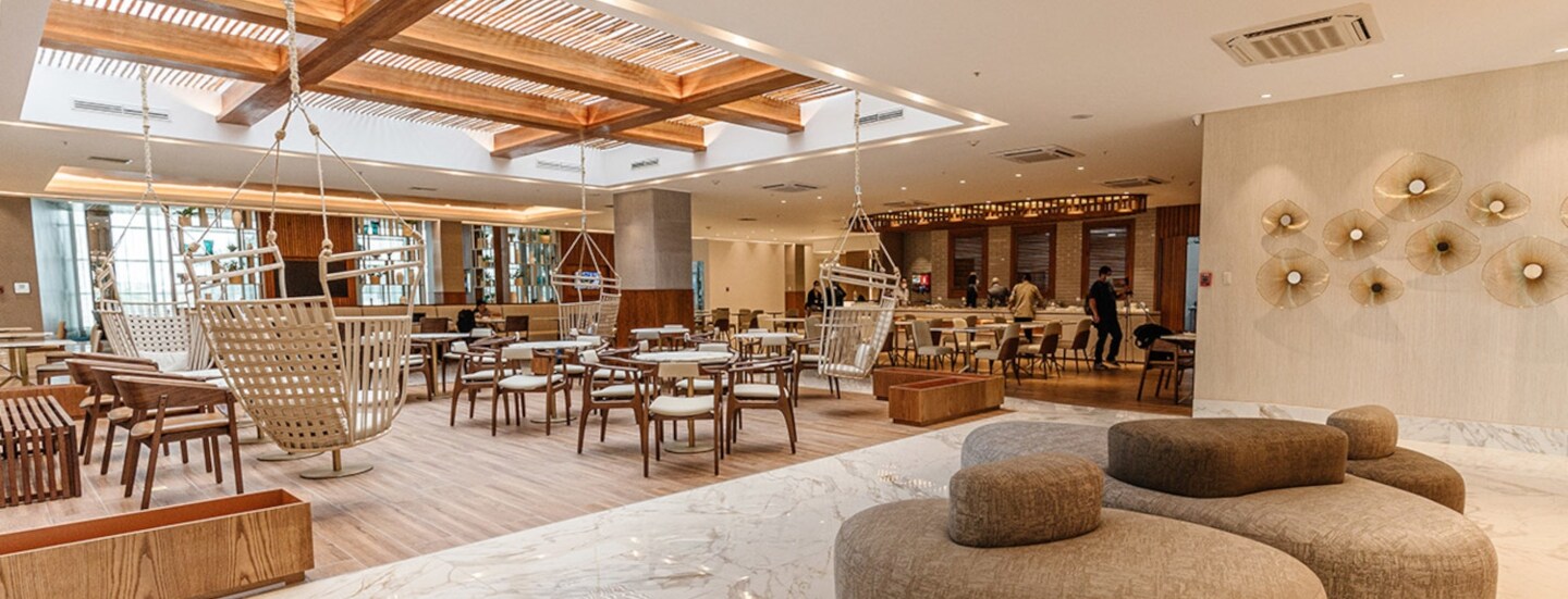 Helle Flughafen-Lounge mit Holzmöbeln und Hängesesseln.