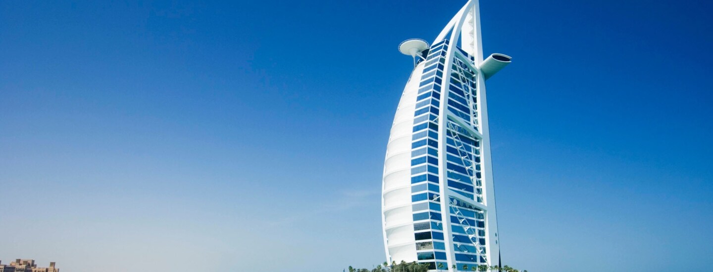 Luxushotel in Segelform auf einer künstlichen Insel an einem Sandstrand.