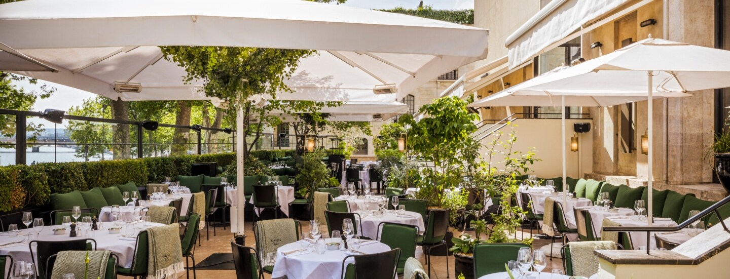 Terrasse eines gehobenen Restaurants mit eingedeckten Tischen.