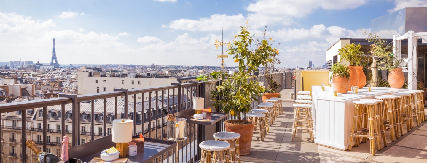 Dachterrasse des Restaurants Perruche mit Blick auf die Dächer von Paris und den Eiffelturm in der Ferne.