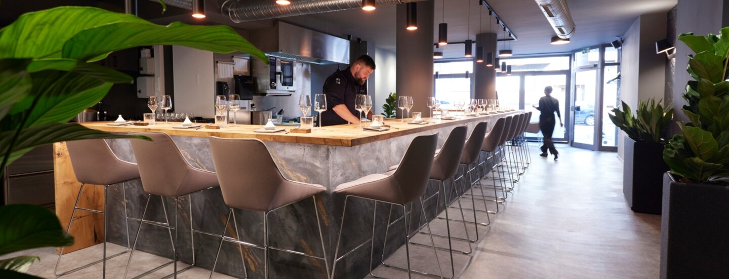 Innenraum des Restaurants Zwanzig23 in Düsseldorf, an dessen Theke Küchenchef Lukas Jakobi steht.