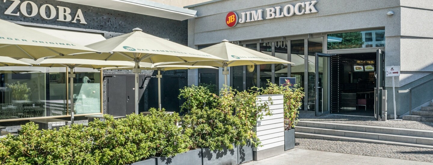 Eingang zu einem Jim Block Restaurant in einem grauen Gebäude.