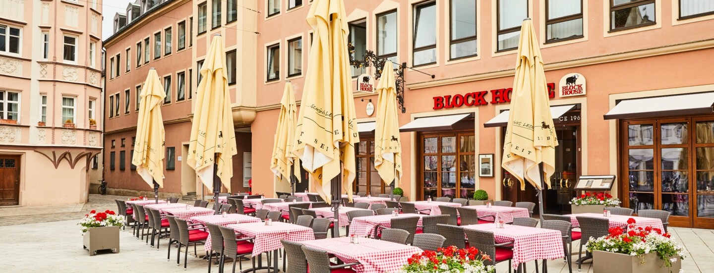 Block House Restaurant mit Außengastronomie auf einem Platz in einer Altstadt.