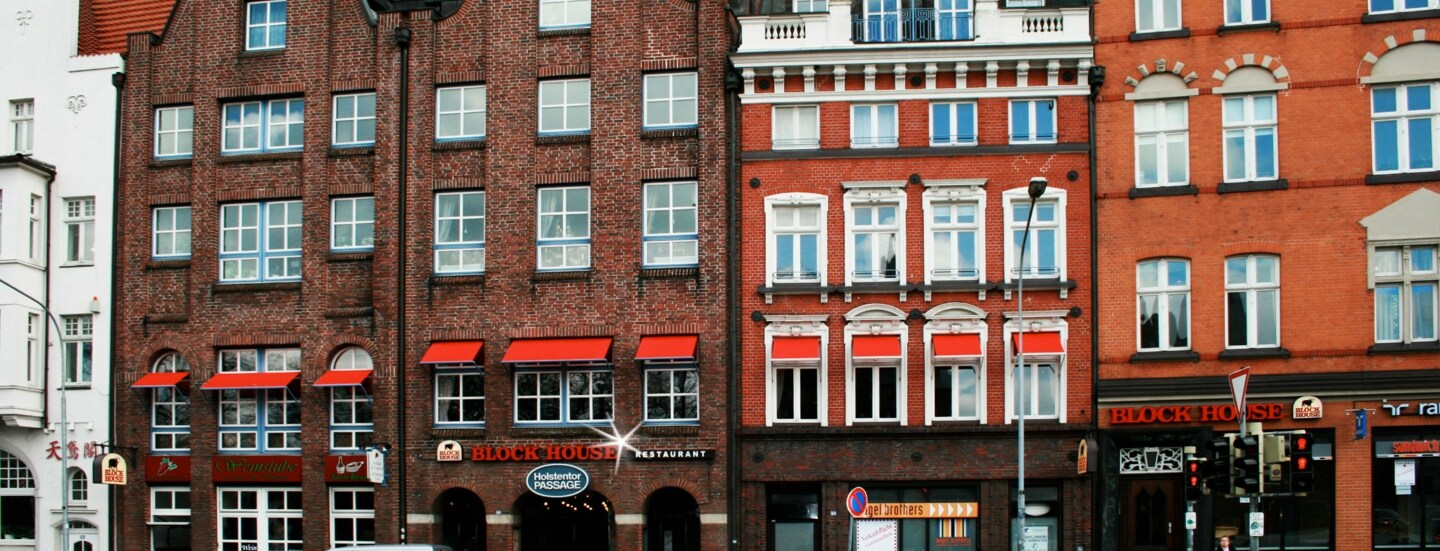 Häuserfront mit Giebelhäusern aus Rotsteinklinker mit Block House Schriftzug.