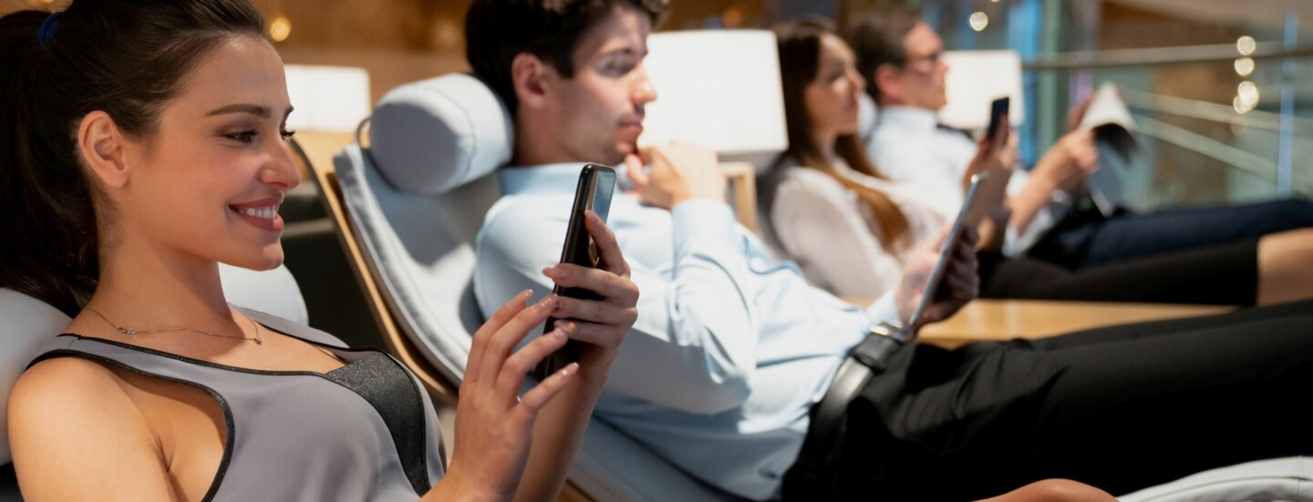 Vier Personen nebeneinander auf Liegen in einer Flughafen-Lounge.