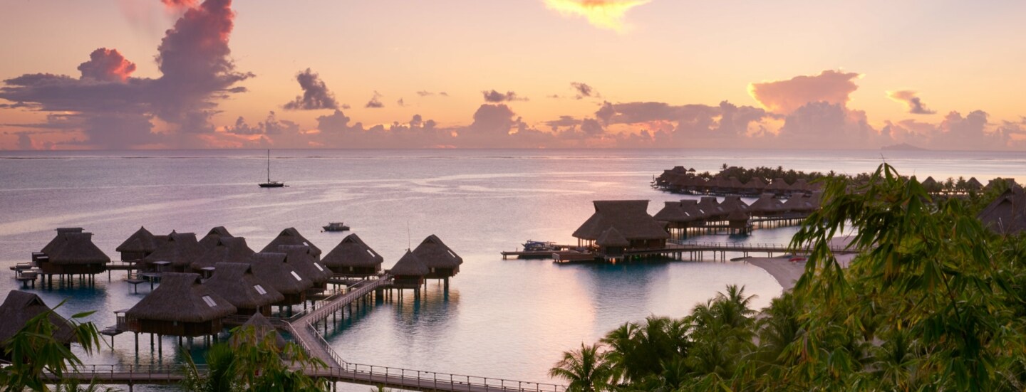 Blick auf die Anlage des Conrad Bora Bora Nui in der Dämmerung, mit seinen friedlich gelegenen Villen auf dem Wasser