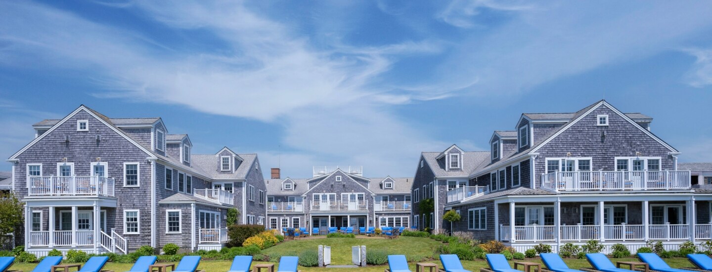 Blick auf die in U-Form stehenden Cottages des White Elephant, mit blau gepolsterten Liegen im Vordergrund.