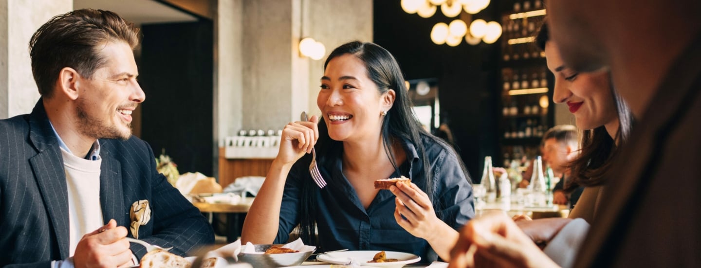 Vier fröhliche Menschen an einem Tisch im Restaurant.