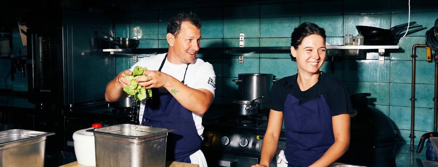 Koch und Köchin bereiten Salat und Fisch in der Restaurantküche vor.