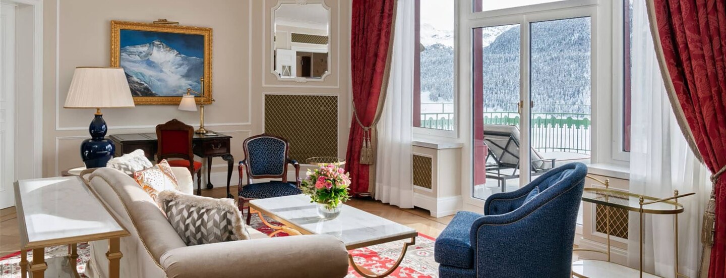 Edle, helle Hotelsuite mit Terrasse mit Blick in schneebedeckte Berglandschaft.