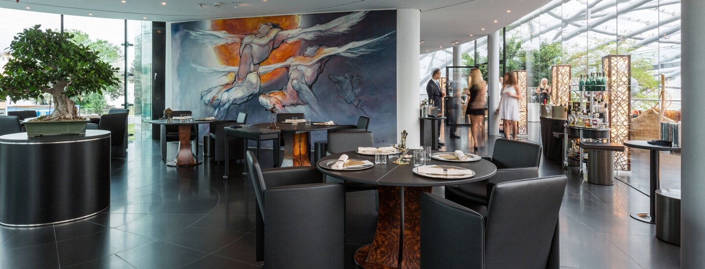 Stehende Personen in einem modernen Restaurant in einem lichtdurchfluteten Gebäude mit Glaskuppel.