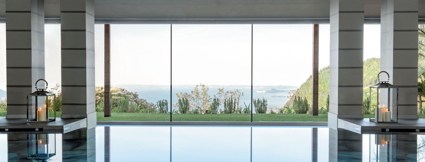 Indoor-Pool vor Panoramafenster mit Seeblick.