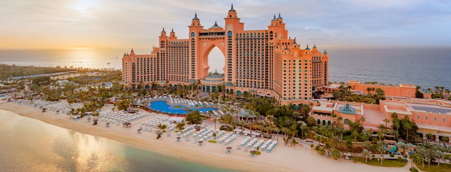 Luxuriöser Hotelkomplex mit Türmen auf einer Insel mit Gartenanlage und Pool an weißem Sandstrand.