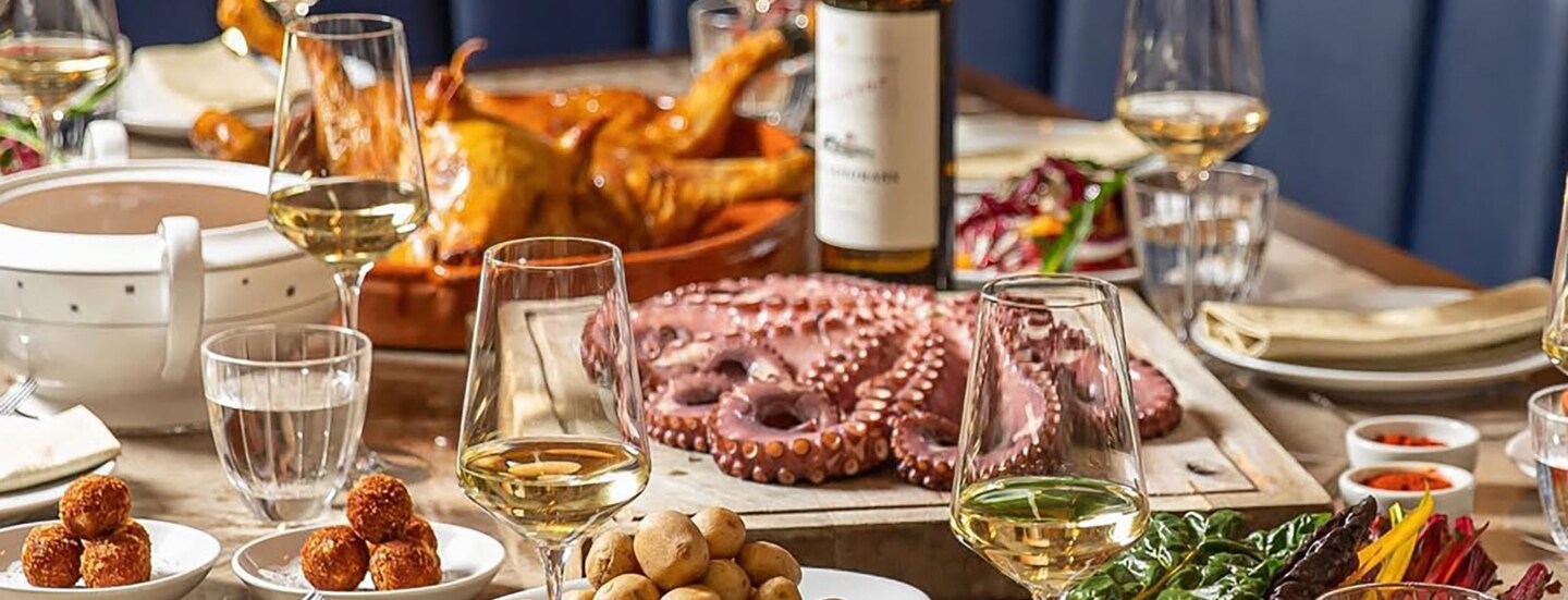 Restauranttisch mit Tapasgerichten und Tintenfisch mit Weingläsern.