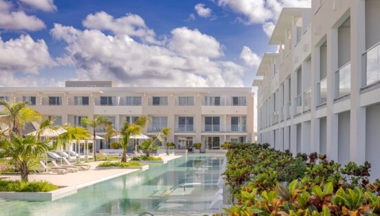 Moderne, dreistöckige Hotelanlage mit begrünter Poollandschaft.