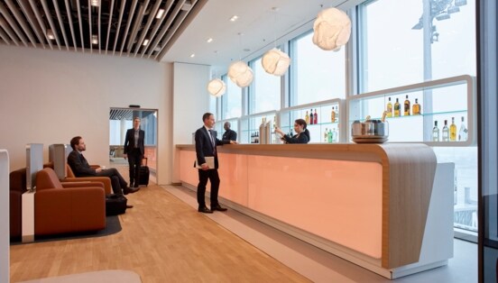 Personen in einer modernen Flughafenlounge mit Bar.