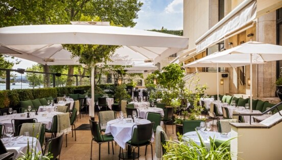 Terrasse eines gehobenen Restaurants mit eingedeckten Tischen.