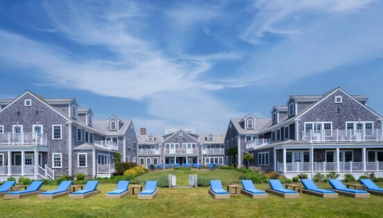 Blick auf die in U-Form stehenden Cottages des White Elephant, mit blau gepolsterten Liegen im Vordergrund.