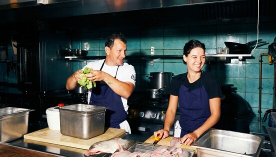 Koch und Köchin bereiten Salat und Fisch in der Restaurantküche vor.
