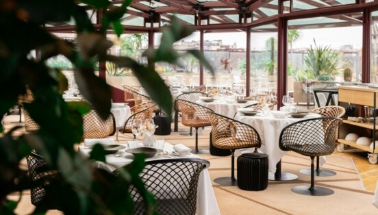 Interieur-Aufnahme eines modernen Restaurants mit gedeckten Tischen und bodentiefen Fenstern, die den Blick auf Paris freigeben.