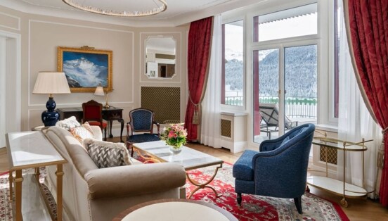 Edle, helle Hotelsuite mit Terrasse mit Blick in schneebedeckte Berglandschaft.