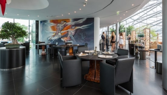 Stehende Personen in einem modernen Restaurant in einem lichtdurchfluteten Gebäude mit Glaskuppel.