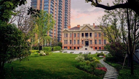 Hotelanlage mit historischem Gebäude neben einem Hochhaus in einer Gartenanlage.