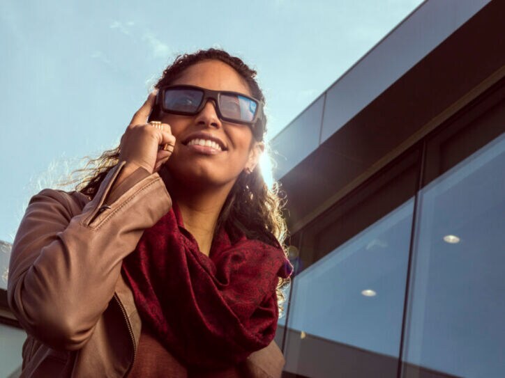 Eine Frau trägt eine Sonnenbrille die sie mit dem Fingern antippt