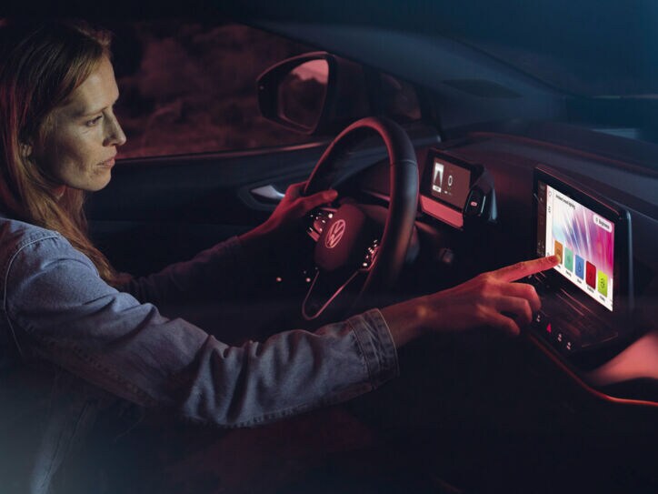 Ein Frau sitzt am Steuer ihres Autos und benutzt das intelligente System ihres Golfs.